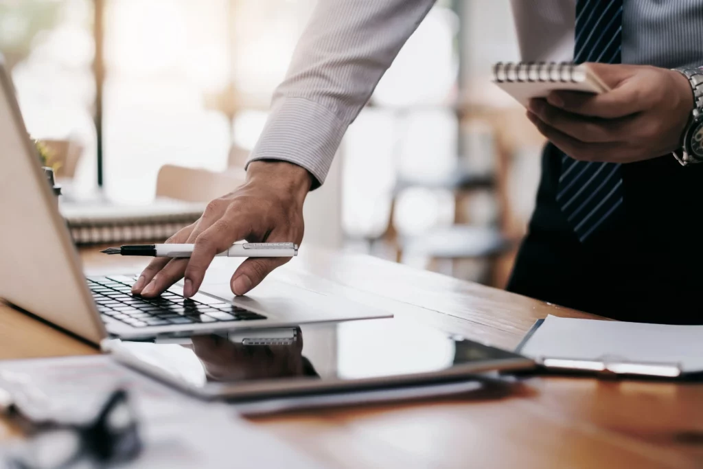 Ein Geschaeftsmann arbeitet mit Laptop und Smartphone an Finanzberichten.